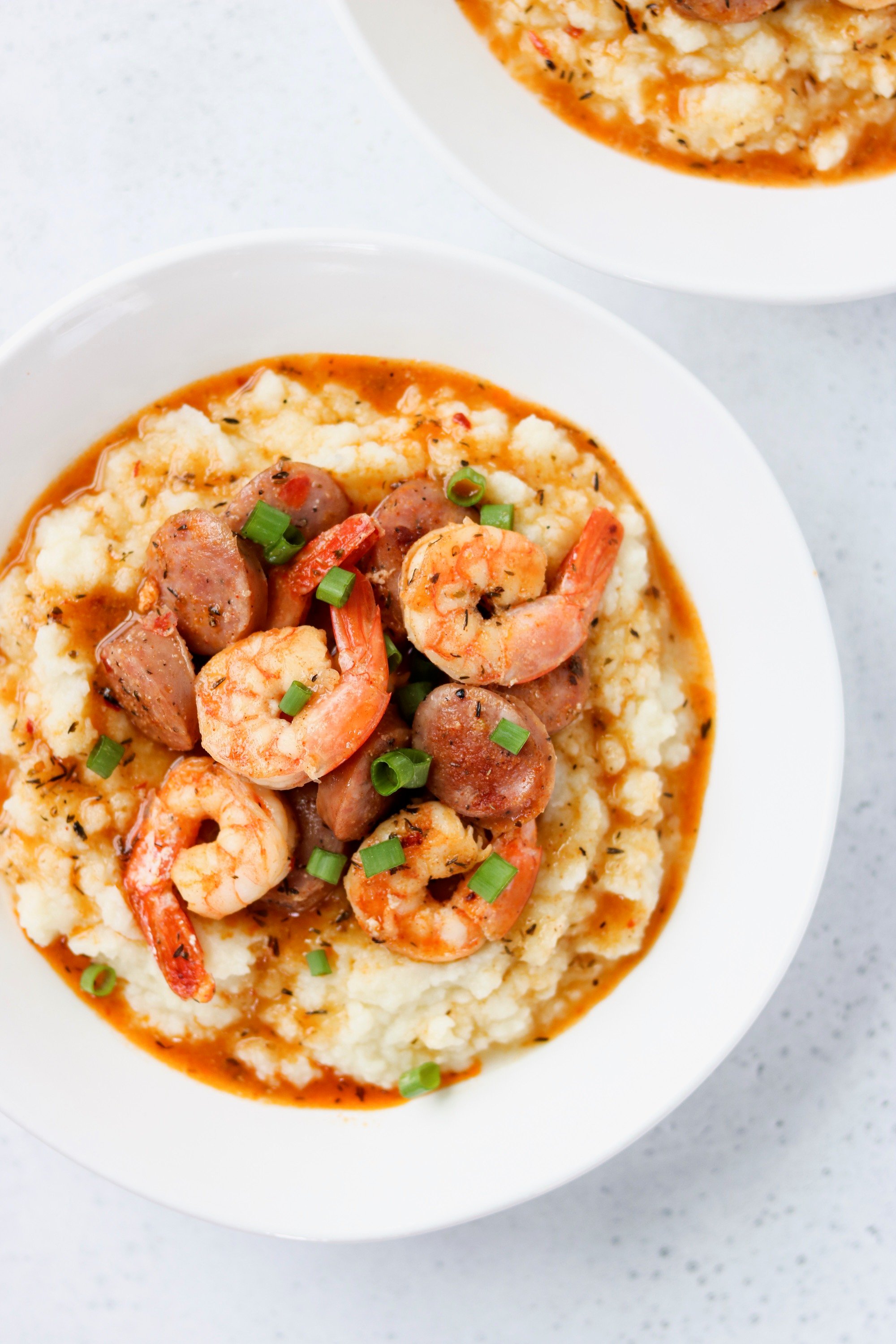Keto shrimp and cauliflower grits with sausage in a white bowl
