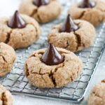 Gluten Free Peanut Butter Blossoms with a Hersey's kiss on a bread cooling rack