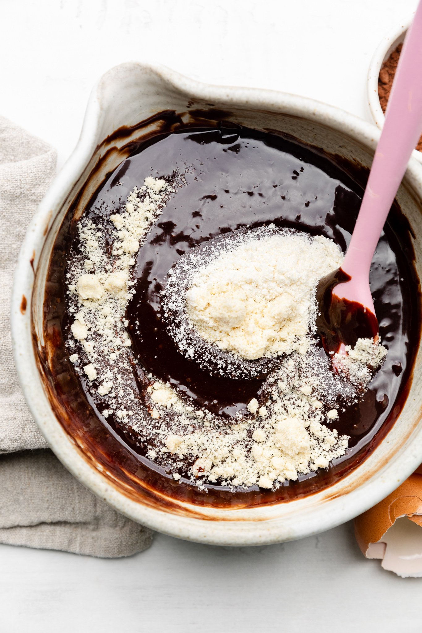 chocolate and almond flour in a mixing bowl with a pink spatula