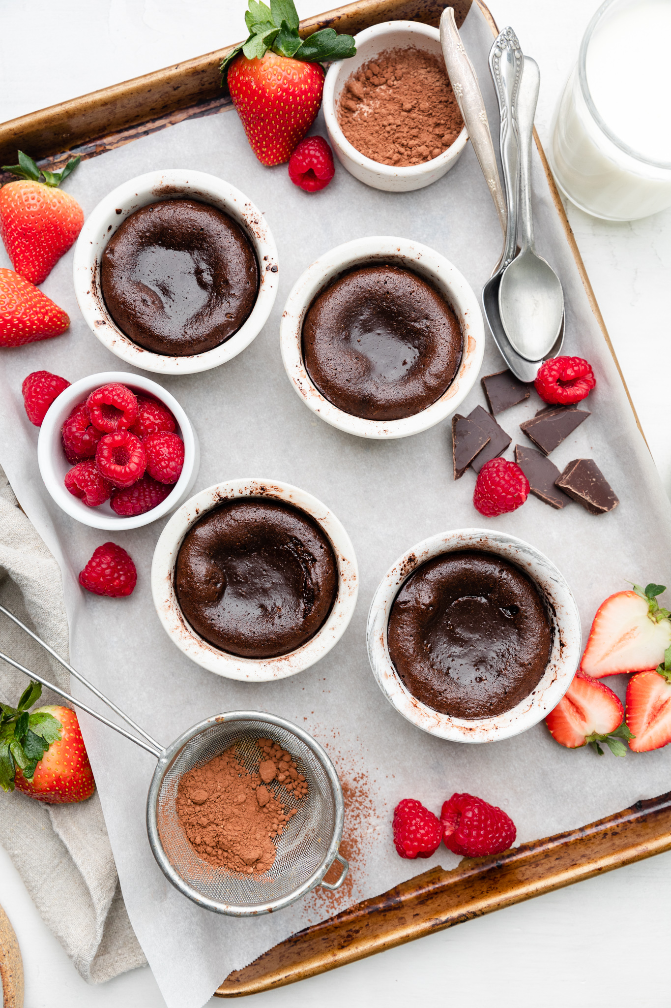gluten-free lava cakes on a parchment-lined baking sheet with berries