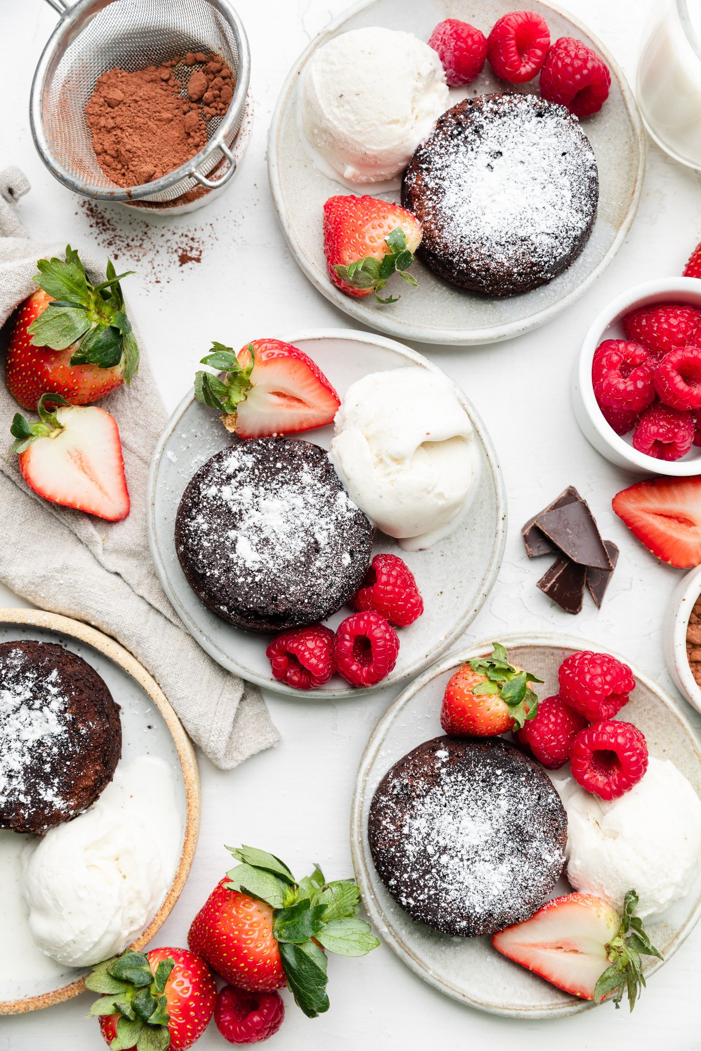mini chocolate cake on 4 different plates with raspberries and strawberries and vanilla ice cream