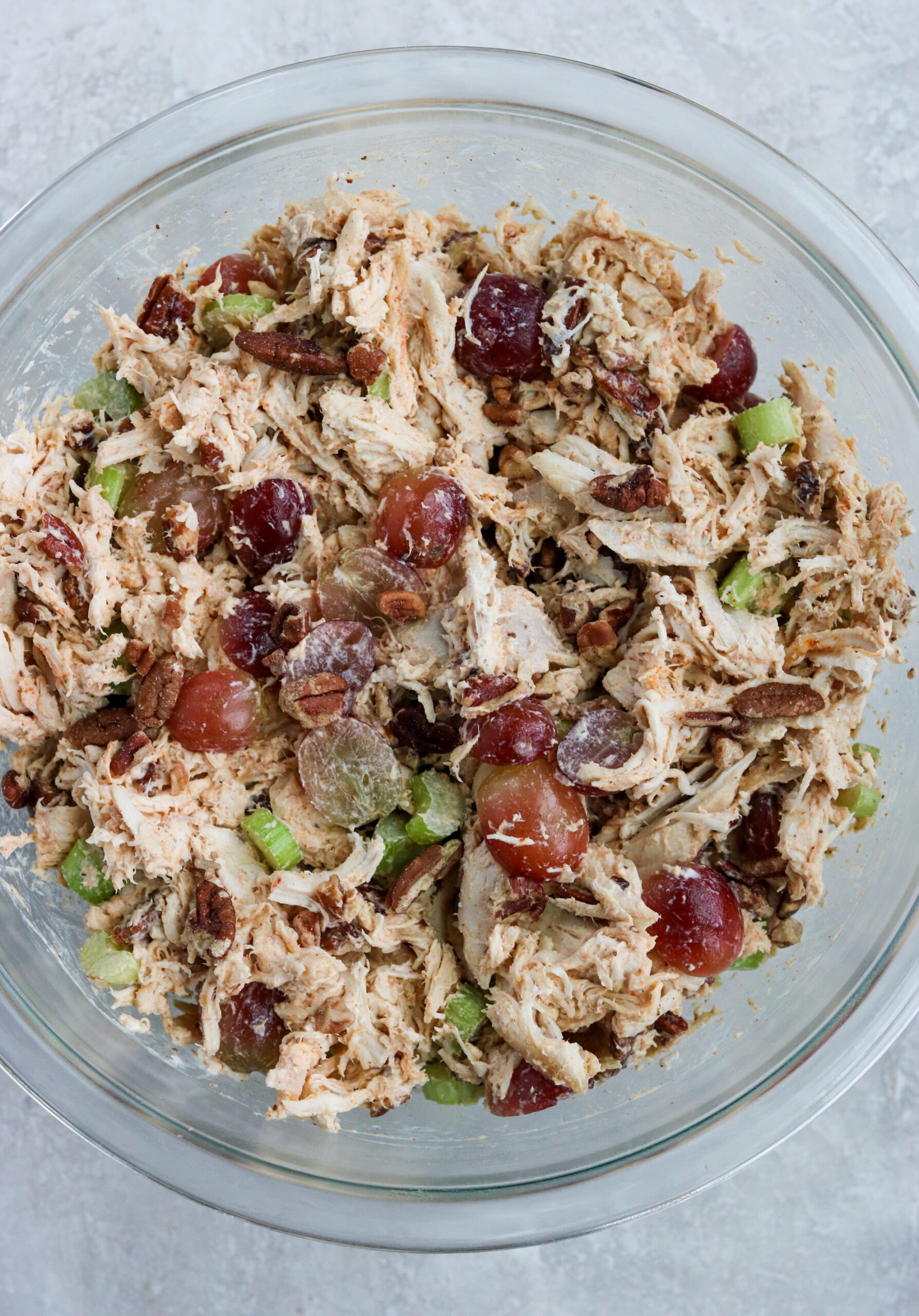 ingredients in a glass bowl with grapes, pecans, and celery
