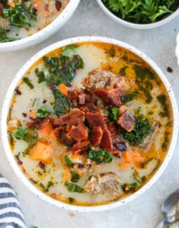 Whole30 Zuppa Toscana in a white bowl topped with bacon and parsley
