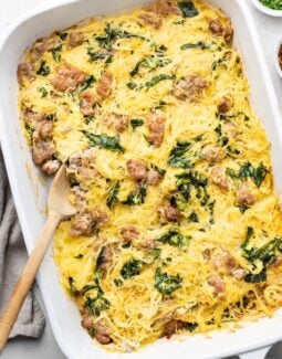 Tuscan Spaghetti Squash Casserole with sausage and kale in a white dish with a spoon