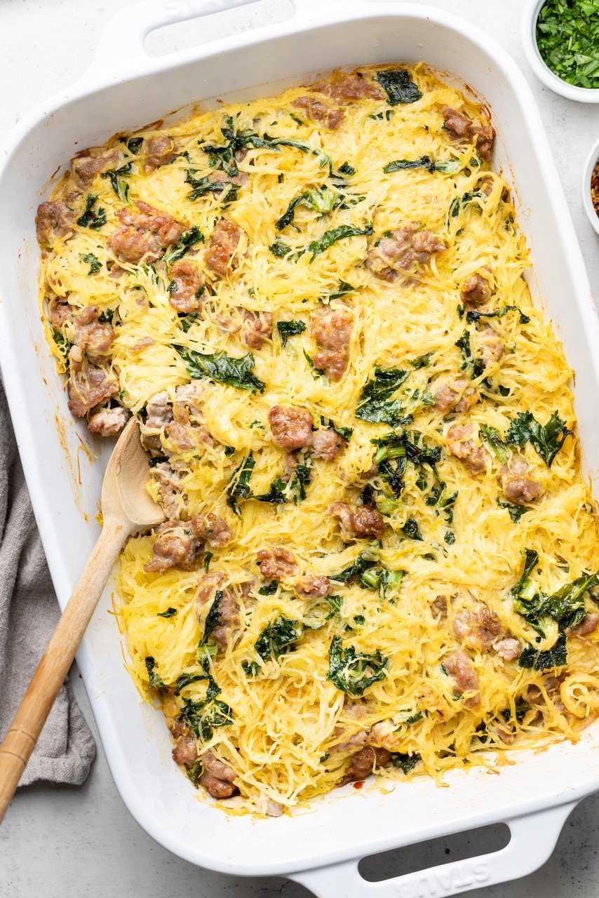 Tuscan Spaghetti Squash Casserole with sausage and kale in a white dish with a spoon