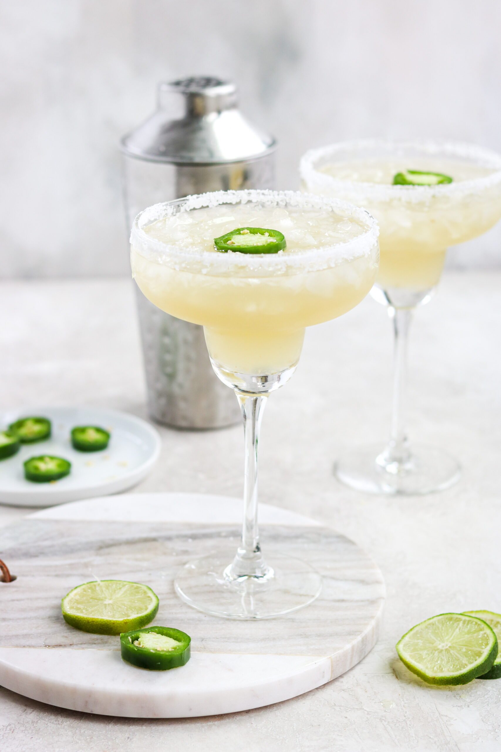 Spicy Skinny Margaritas with salt, jalapeno slices, and lime with a shaker in the background