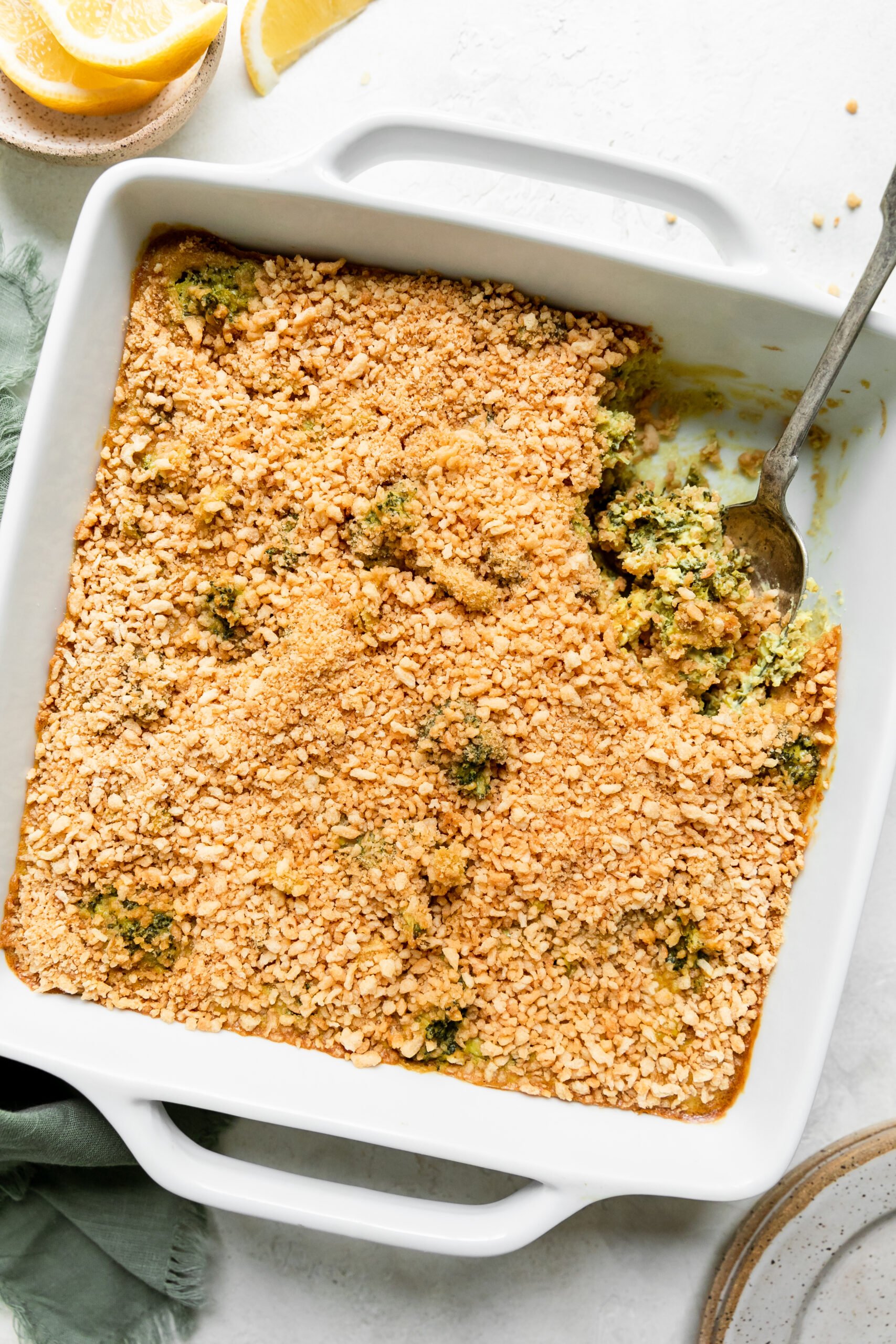 gluten free broccoli casserole in a white dish with a silver spoon scooping out a serving