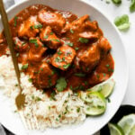 Chicken Tikka Masala with white rice and lime and cilantro in a white bowl