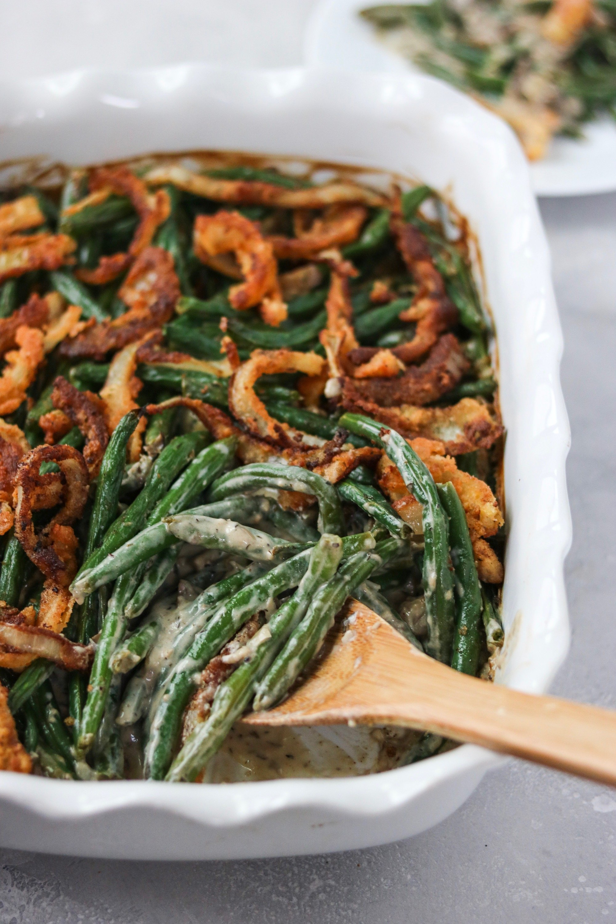 green beans mixed with a creamy, low carb, dairy free mushroom sauce and baked with crispy fried onions in a white casserole dish. 