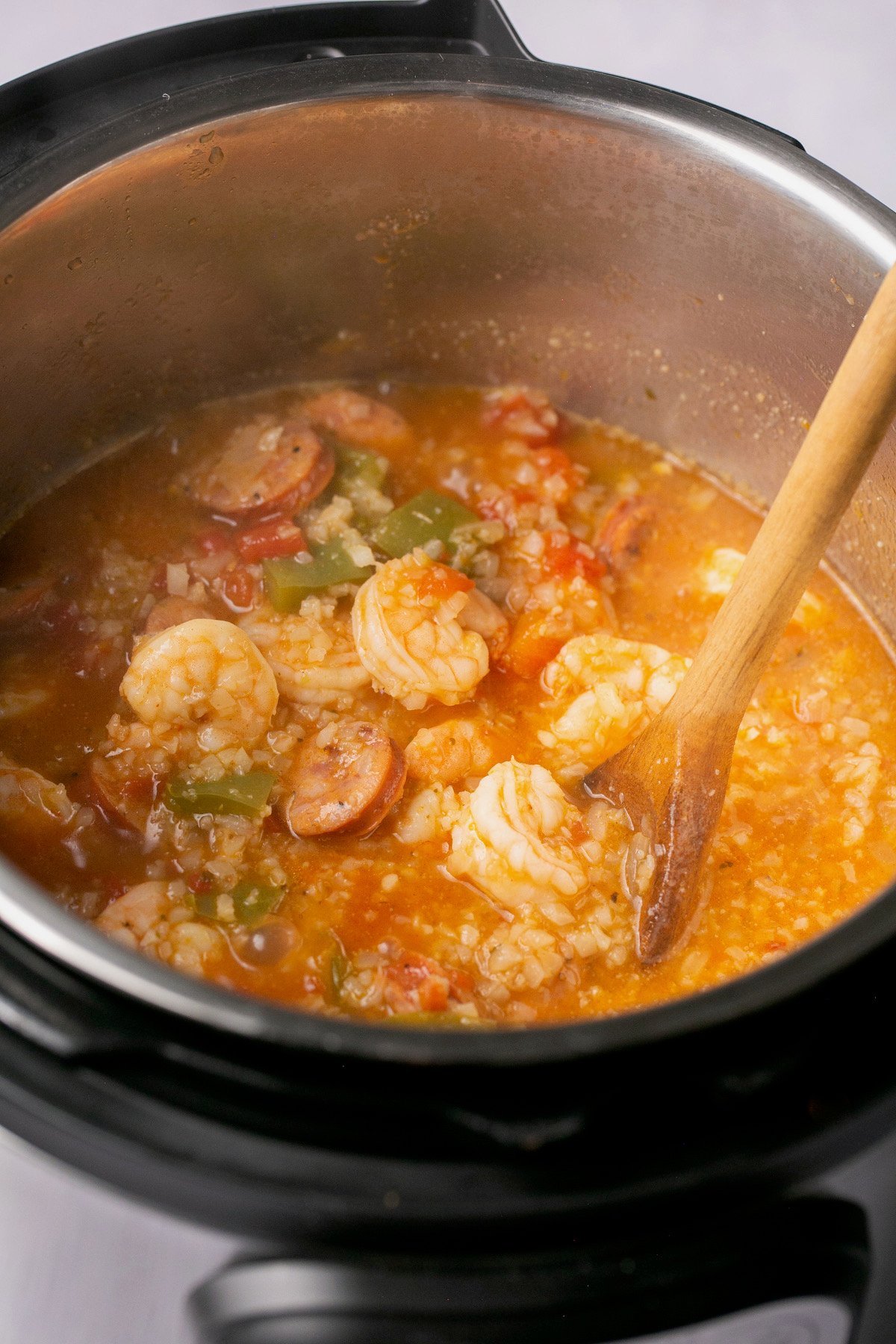 an instant pot filled with shrimp, broth, sausage, and veggies