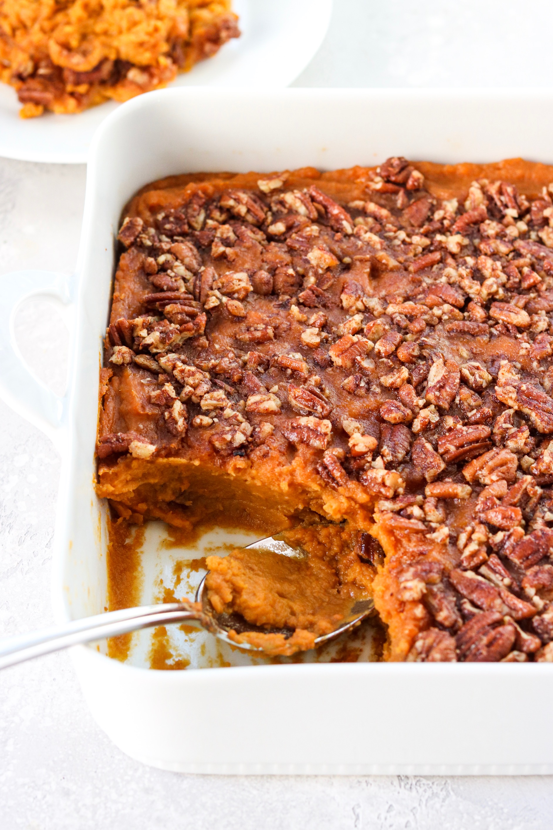 sweet potato casserole with a crunch pecan topping in a white baking dish. 