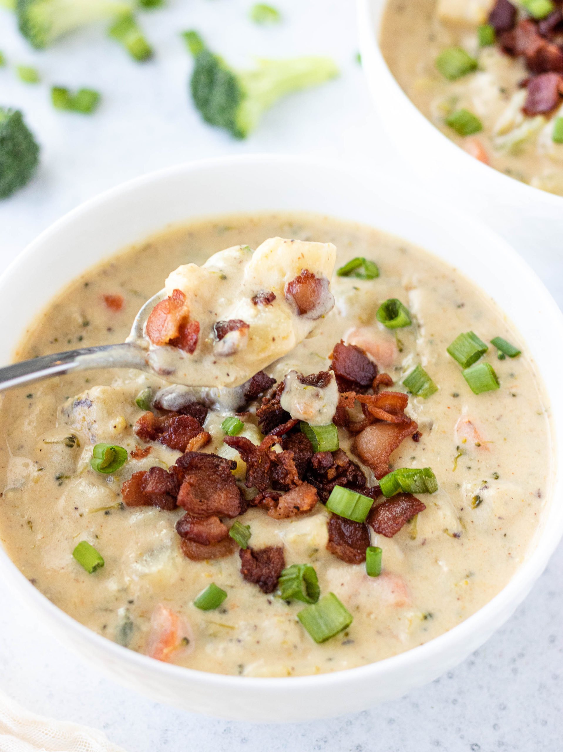 broccoli cheddar and potato soup in a bowl topped with bacon and green onions