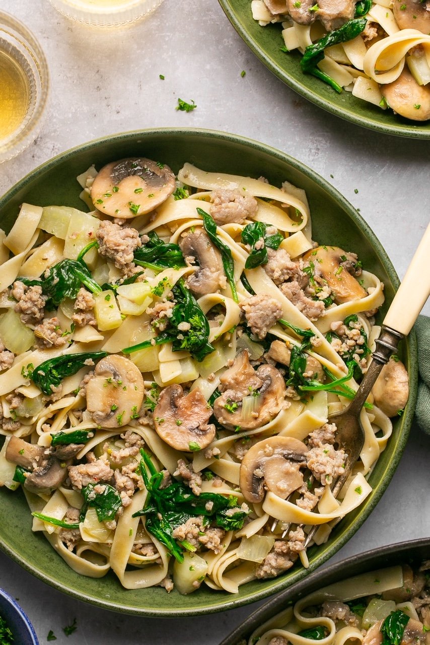 sausage and fennel pasta with spinach and mushrooms in a bowl with a fork