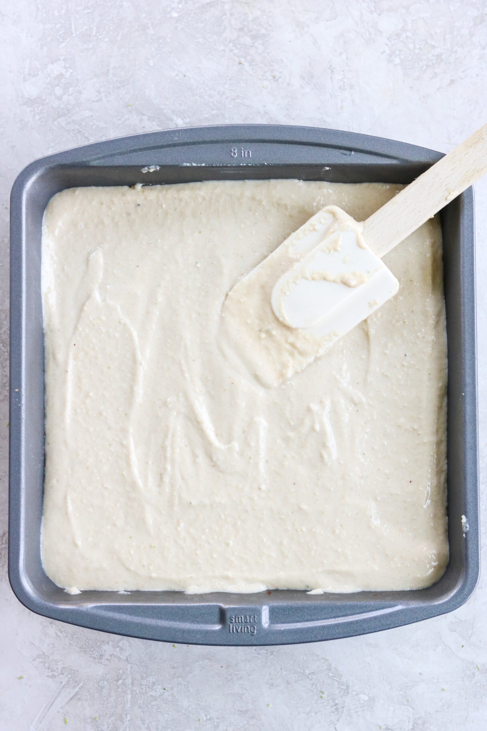 cashew key lime pie bar filling being spread out on the crust with a spatula