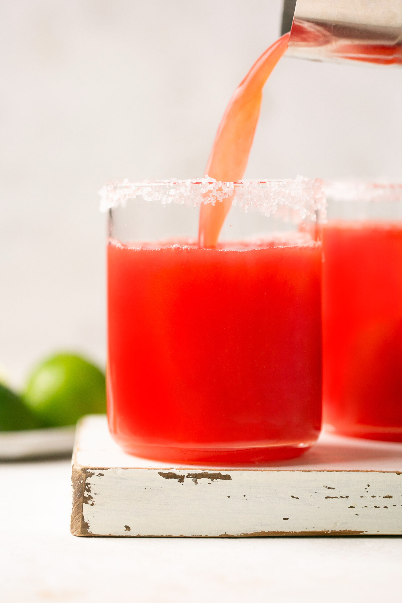a shaker pouring watermelon margarita mix into a glass