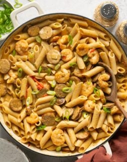 cajun shrimp and sausage pasta in a skillet topped with green onions
