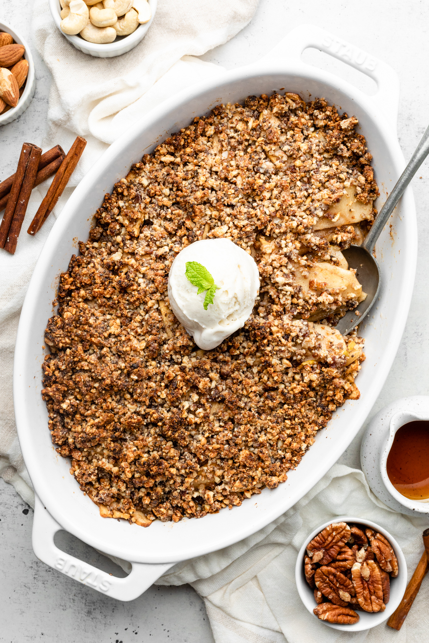gluten free apple crisp in a casserole dish with a spoon taking a scoop out