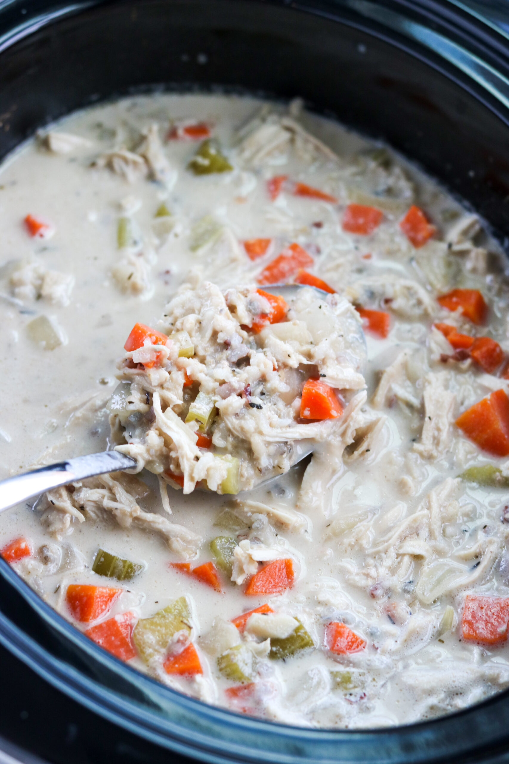 Creamy chicken and rice soup in the slow cooker with a ladle 