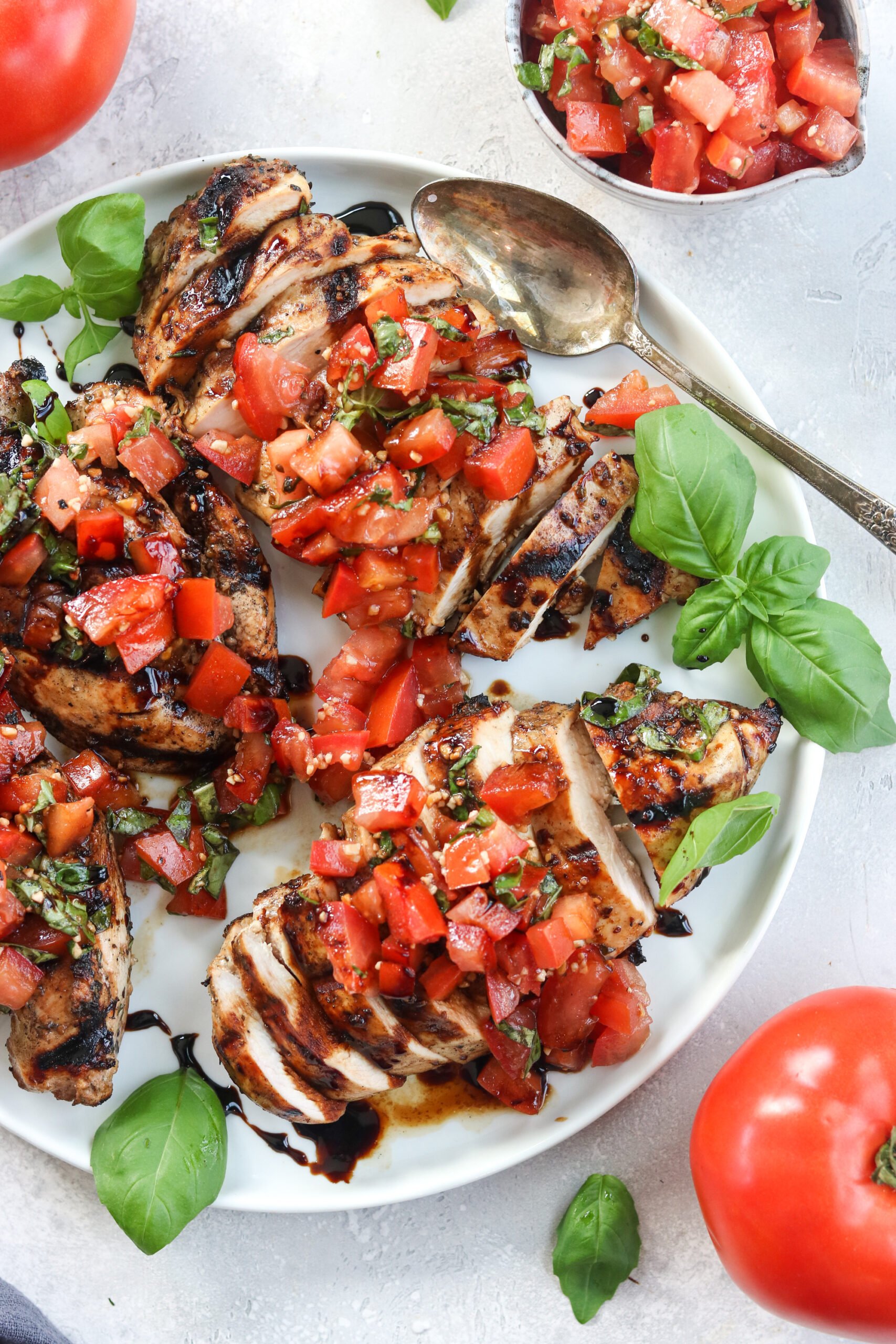 Paleo Grilled Bruschetta Chicken served on a white plate with tomatoes 