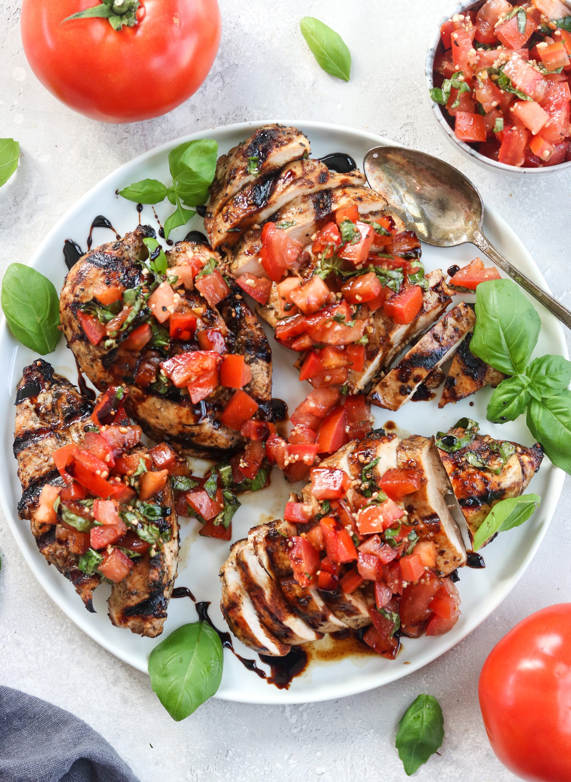 chicken that's Grilled with tomatoes and garnish on a white plate