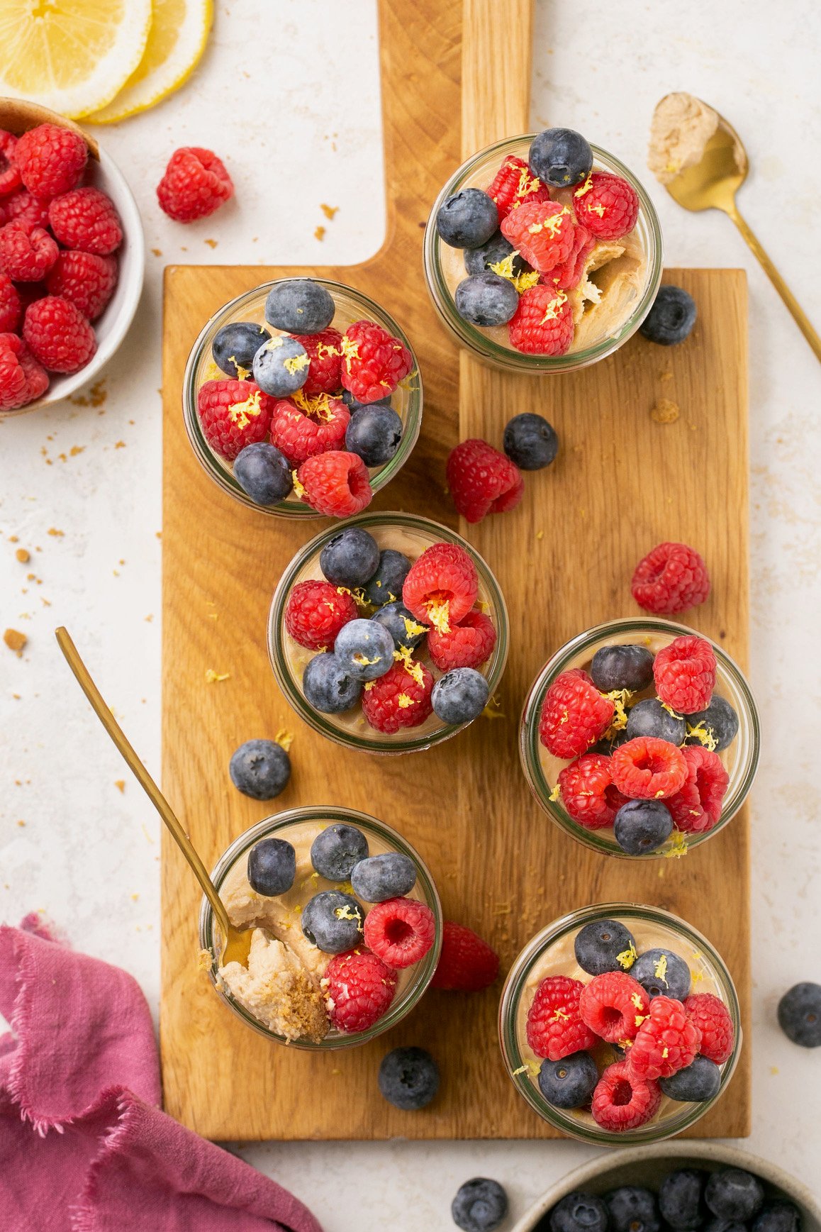 jars of no bake mini cheesecakes on a wooden cutting board 
