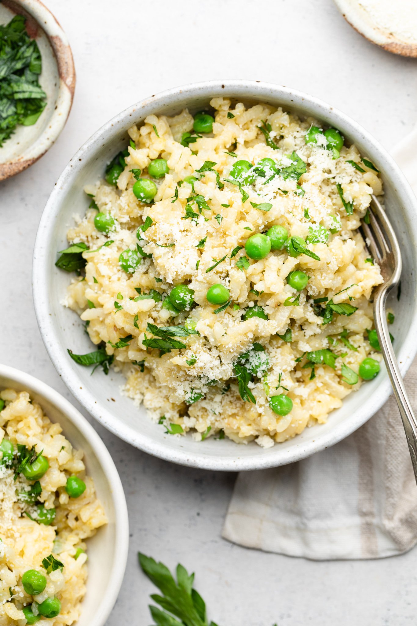 bowl of risotto with peas topped with parsley and parmesan cheese