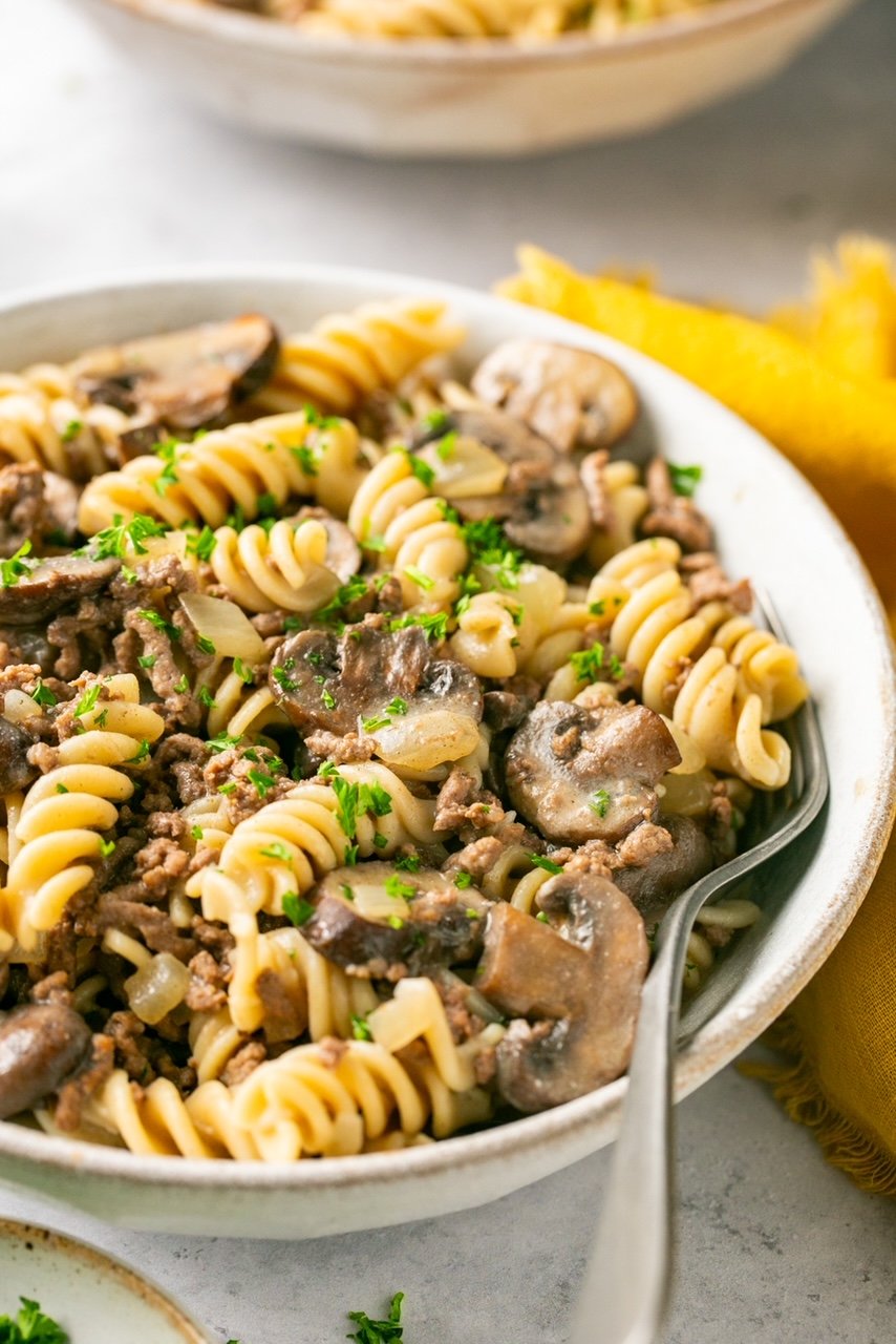a side view close-up of a bowl of ground beef stroganoff with a metal spoon 