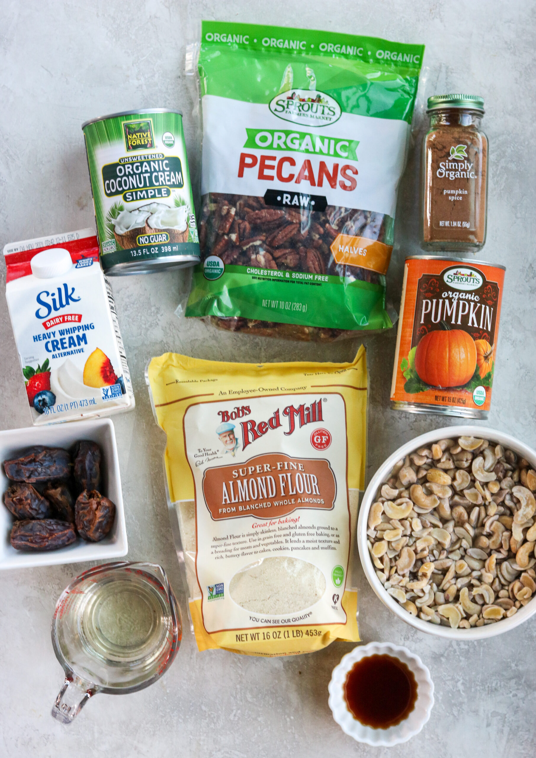 all the ingredients to make the bars: coconut cream, dairy free whipping cream, pitted dates, almond flour, cashews, canned pumpkin, raw pecans, pumpkin pie spice, coconut oil, and vanilla extract.