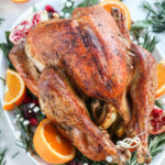 Paleo Roasted Turkey with oranges and pomegranates and herbs on a white platter