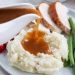 paleo gravy being poured on mashed potatoes with turkey in the background