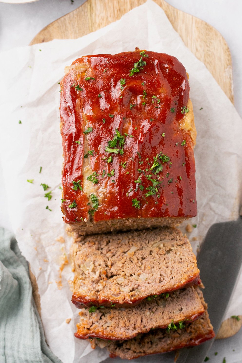 a sliced meatloaf resting on a lined cutting board with a glaze on top