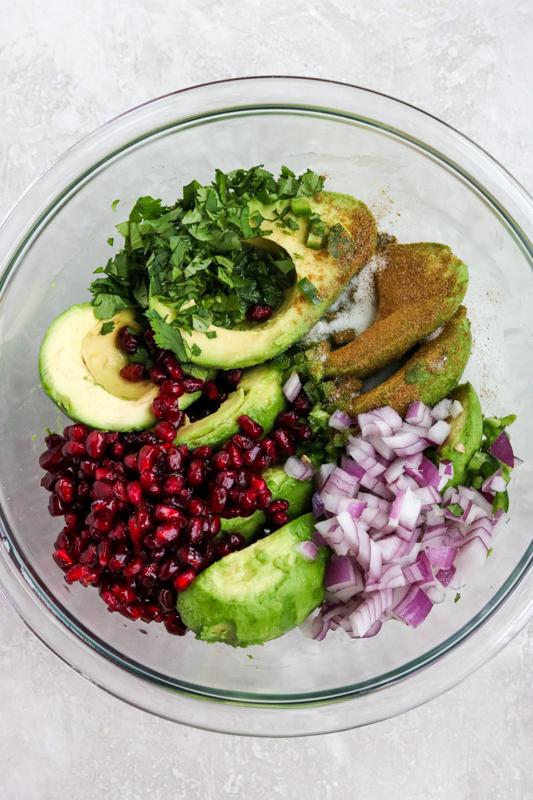 ingredients to make easy pomegranate guacamole in a glass bowl