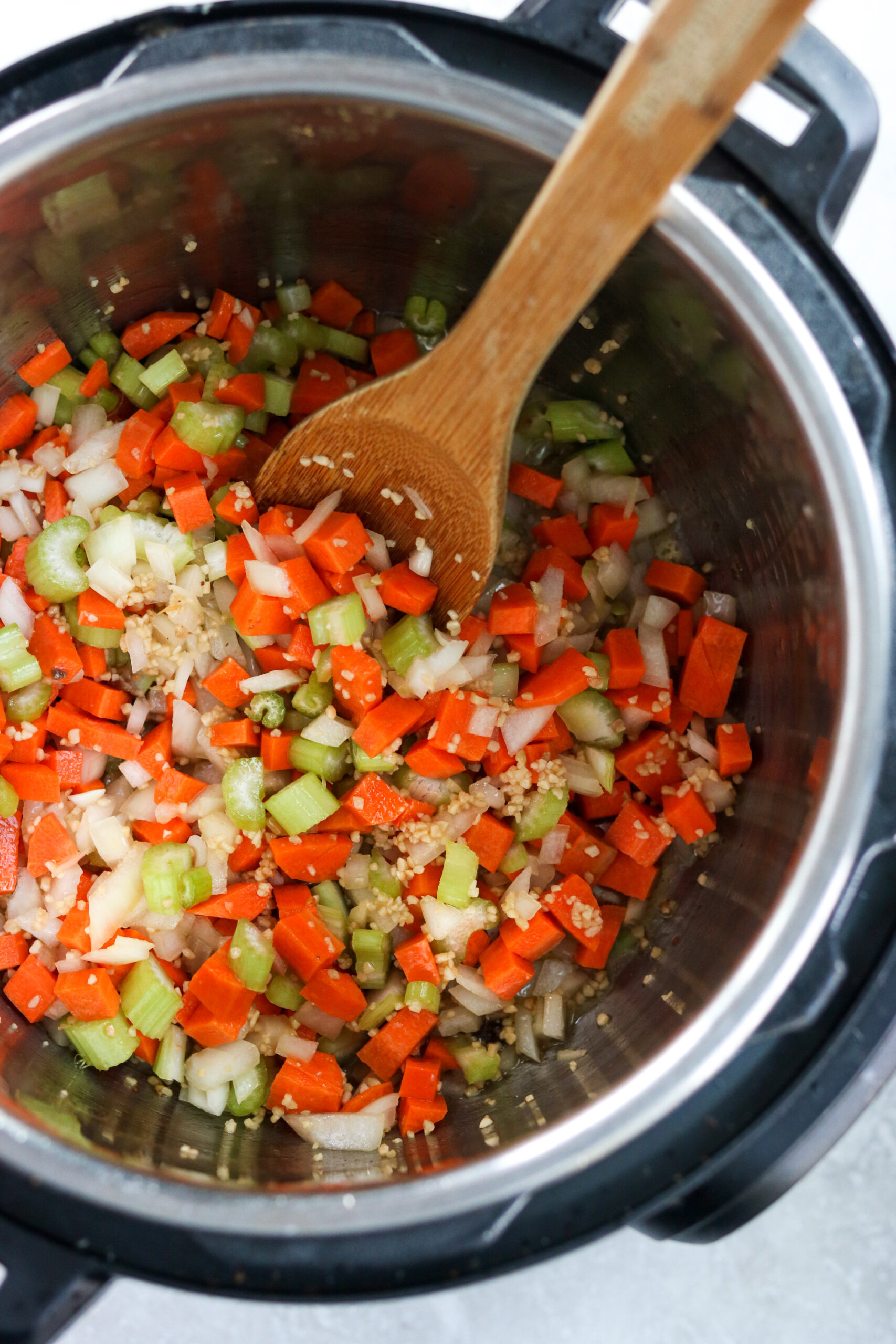 Onions, carrots, celery, and garlic sautéed in olive oil in the Instant Pot with a wooden spoon