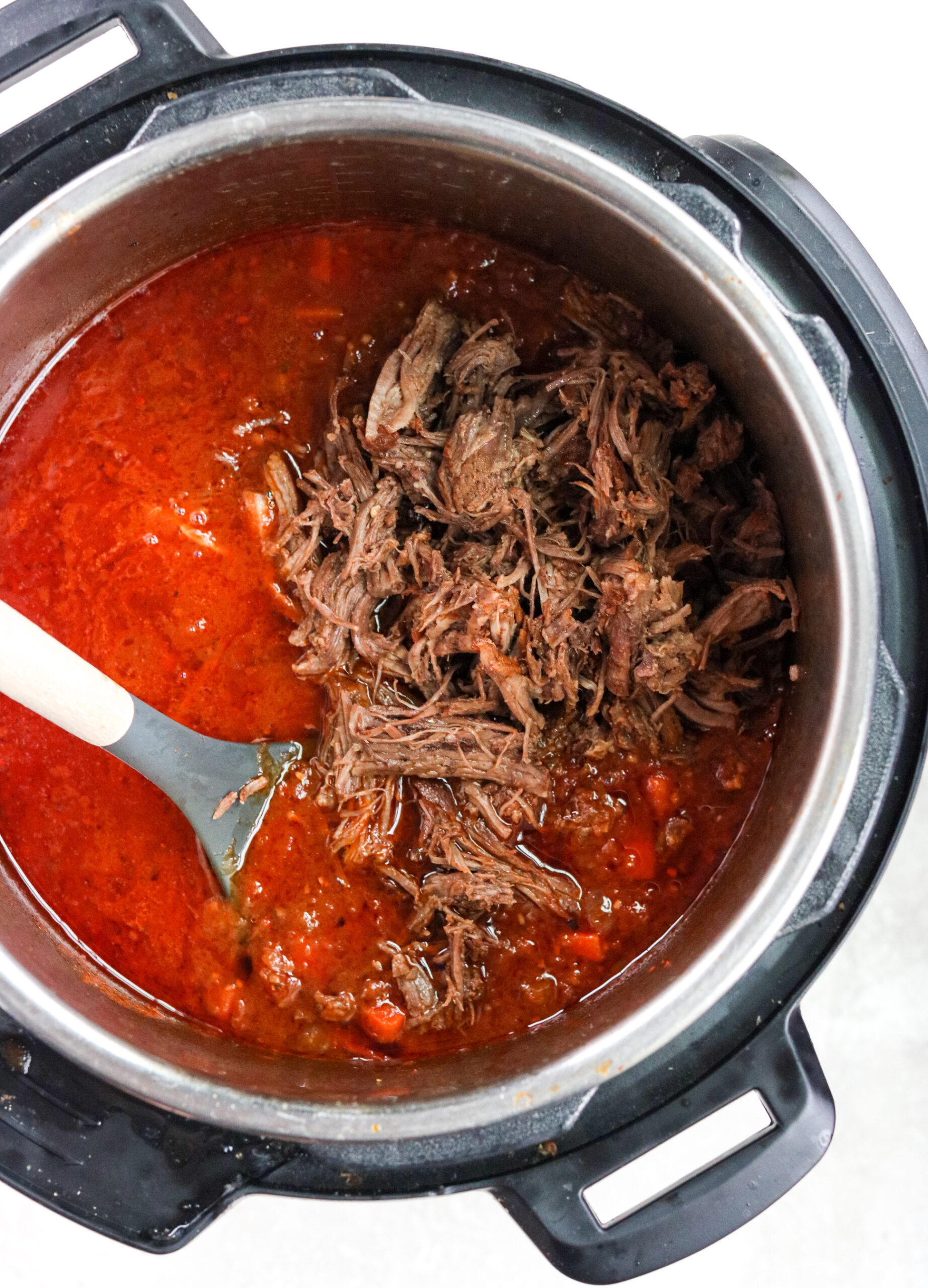 Sauce and shredded beef in the instant pot with a spoon