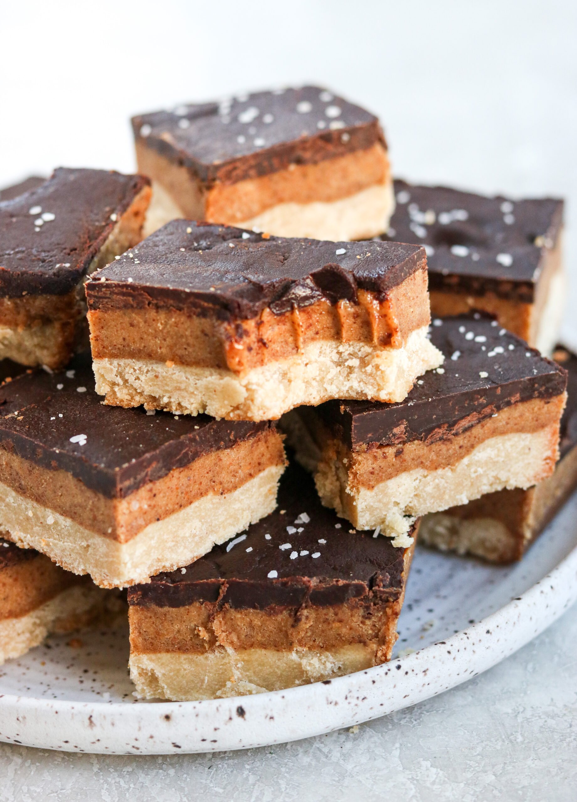 Vegan & gluten free shortbread bars stacked on a plate. One has a bite out of it