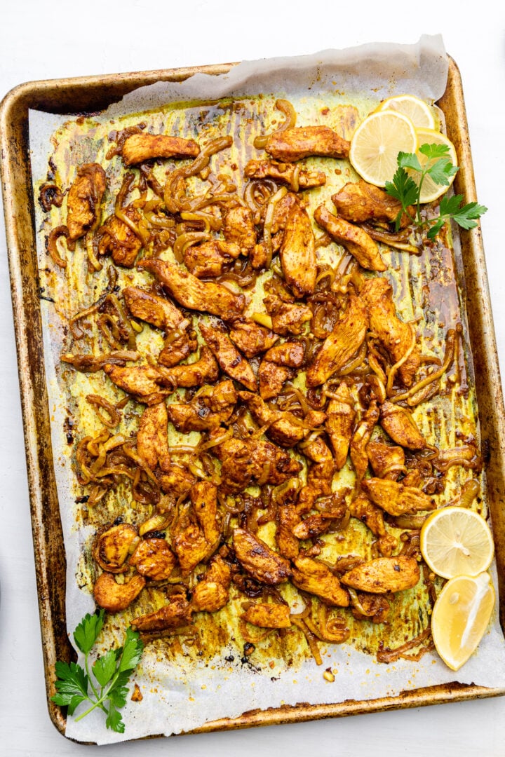 baked marinated chicken on a lined baking sheet