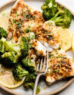 Sheet Pan Cajun Butter Cod with Broccoli on a plate with lemons and a fork
