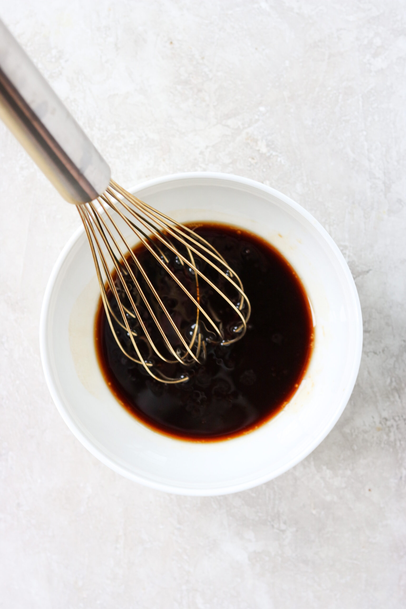 a white bowl with stir fry sauce being whisked by hand