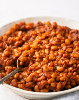 baked beans in a white bowl with a silver spoon