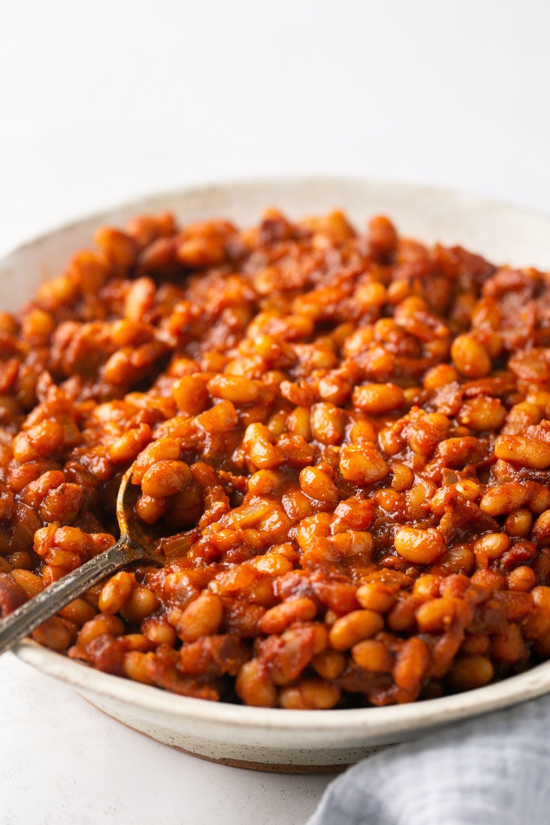 baked beans in a white bowl with a silver spoon