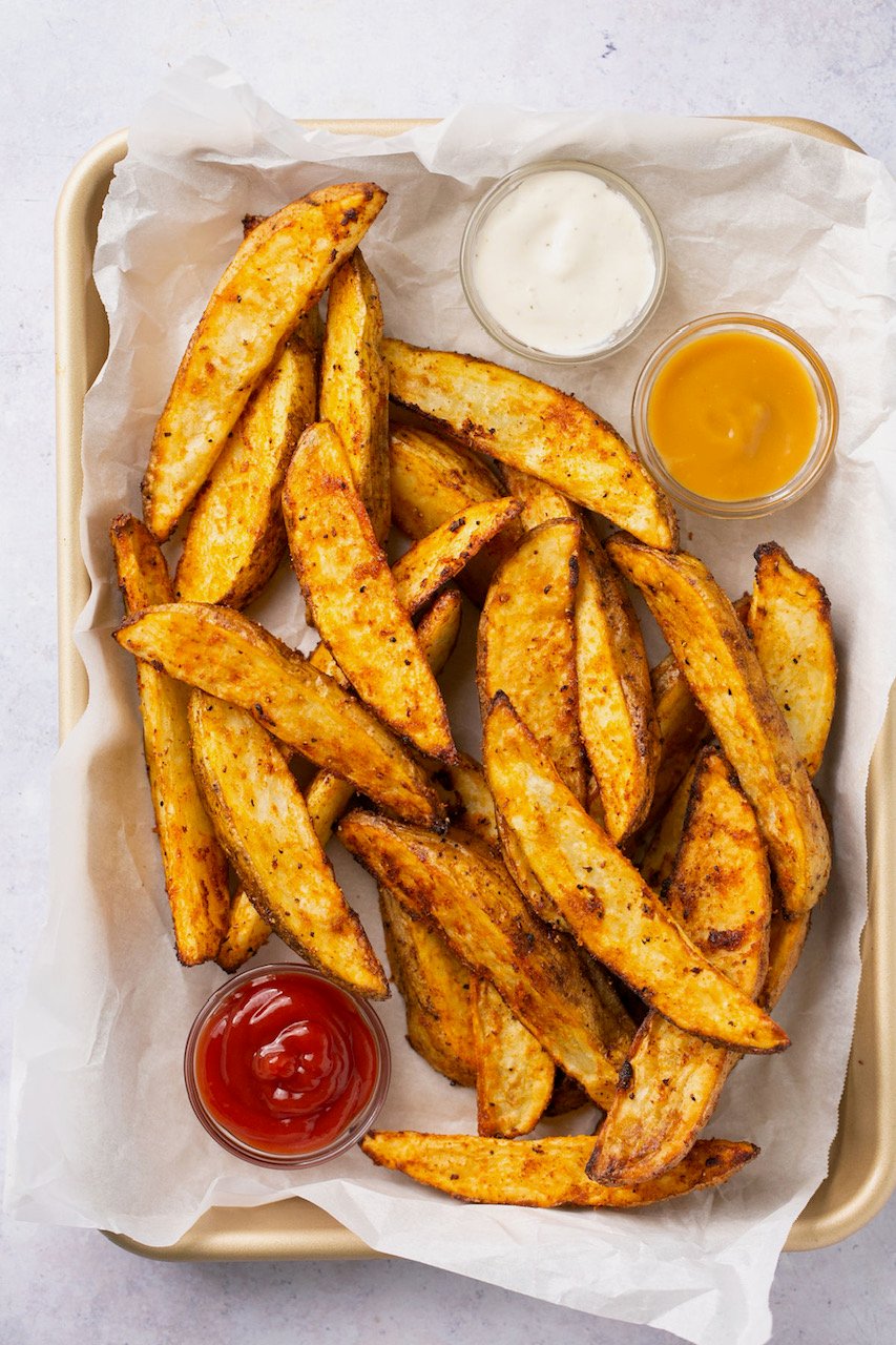 air fryer potato wedges in a basket with 3 dipping sauces