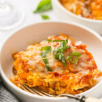 Instant Pot Lasagna in a white bowl topped with basil with a fork