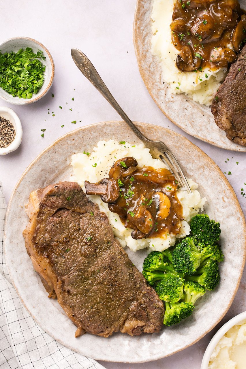 New York Strip on a plate with mashed potatoes, gravy, and broccoli