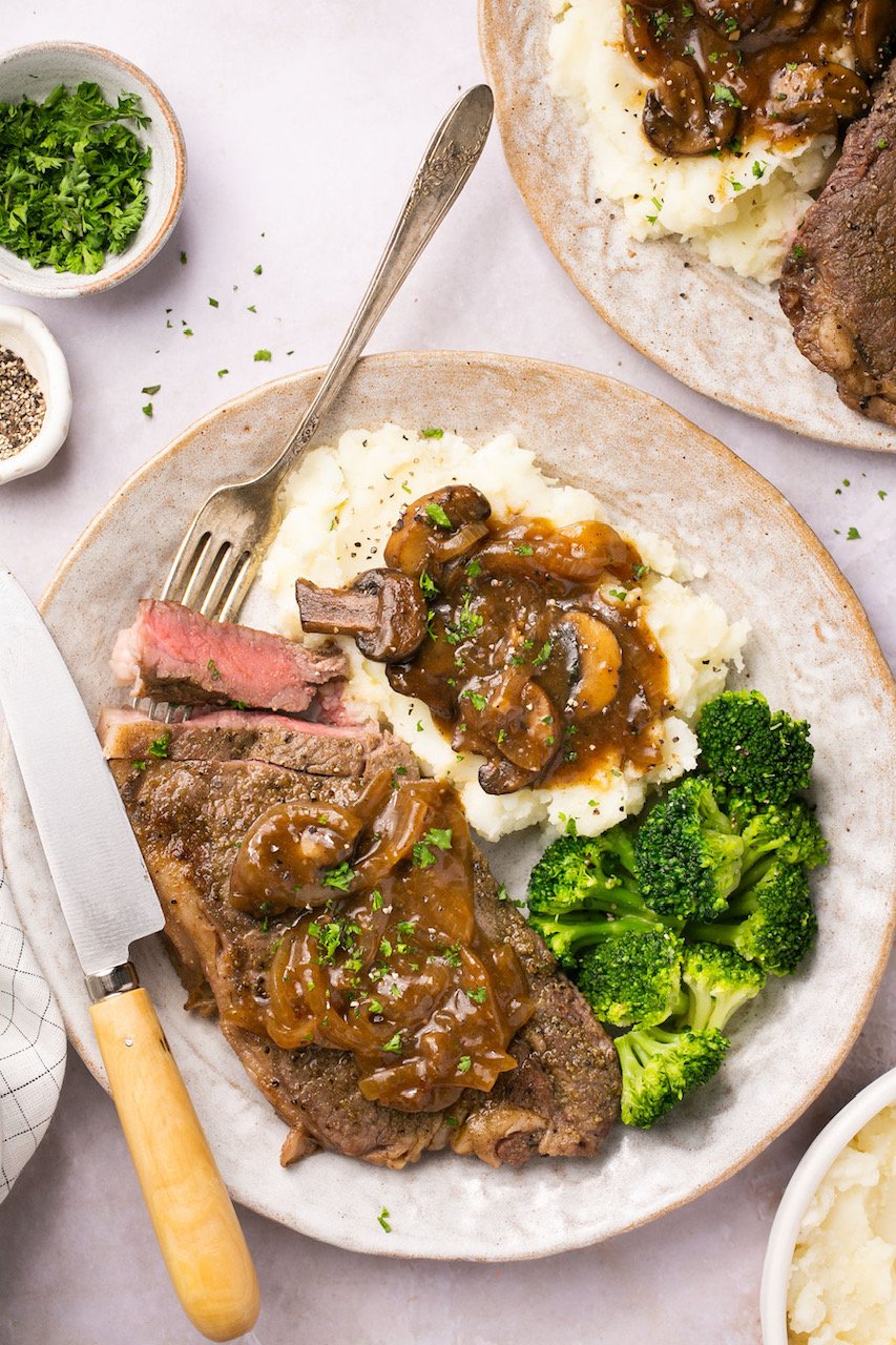 Instant Pot Steak with Homemade Gravy on a plate with mashed potatoes and broccoli and a steak knife