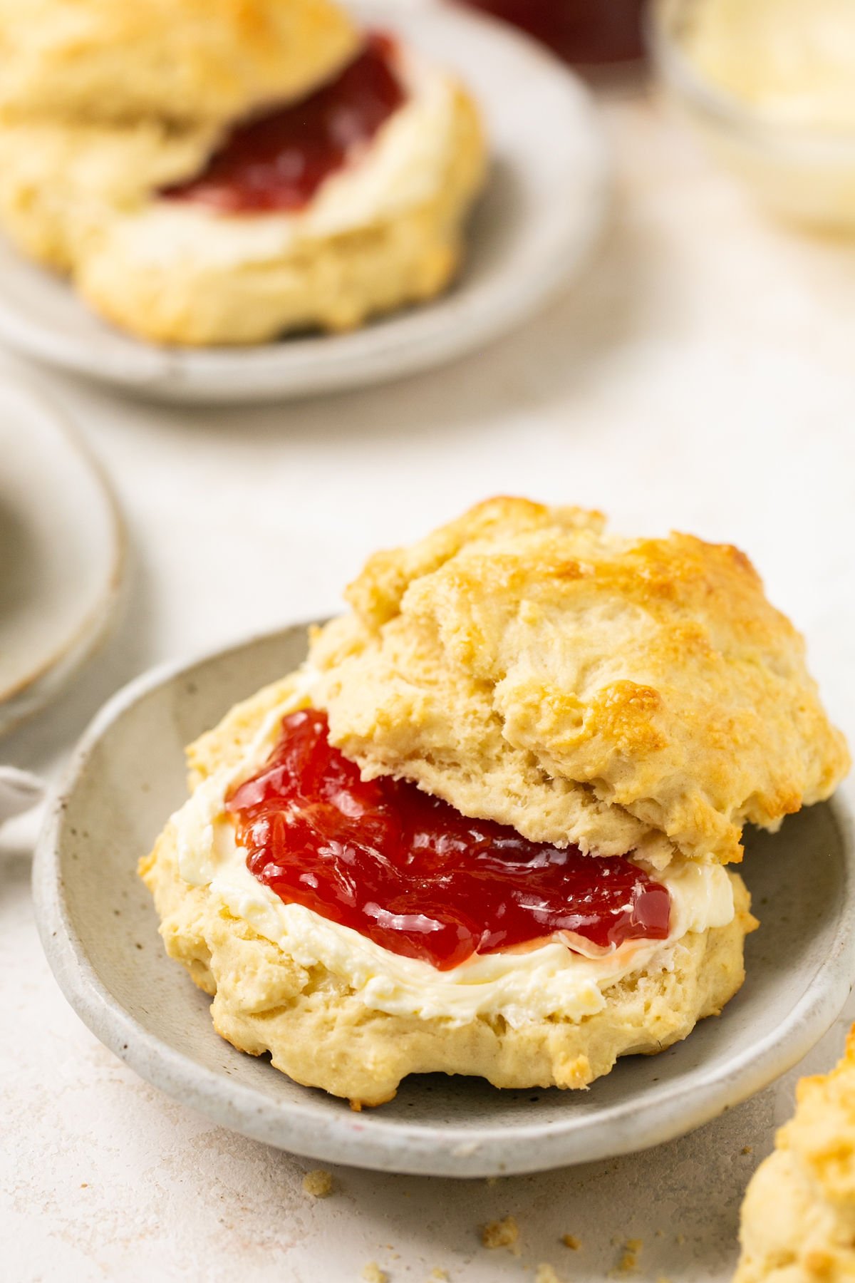 a biscuit cut in half on a gray plate with butter and jam in the middle of it