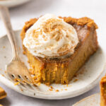 gluten free pumpkin pie on a plate topped with whipped cream