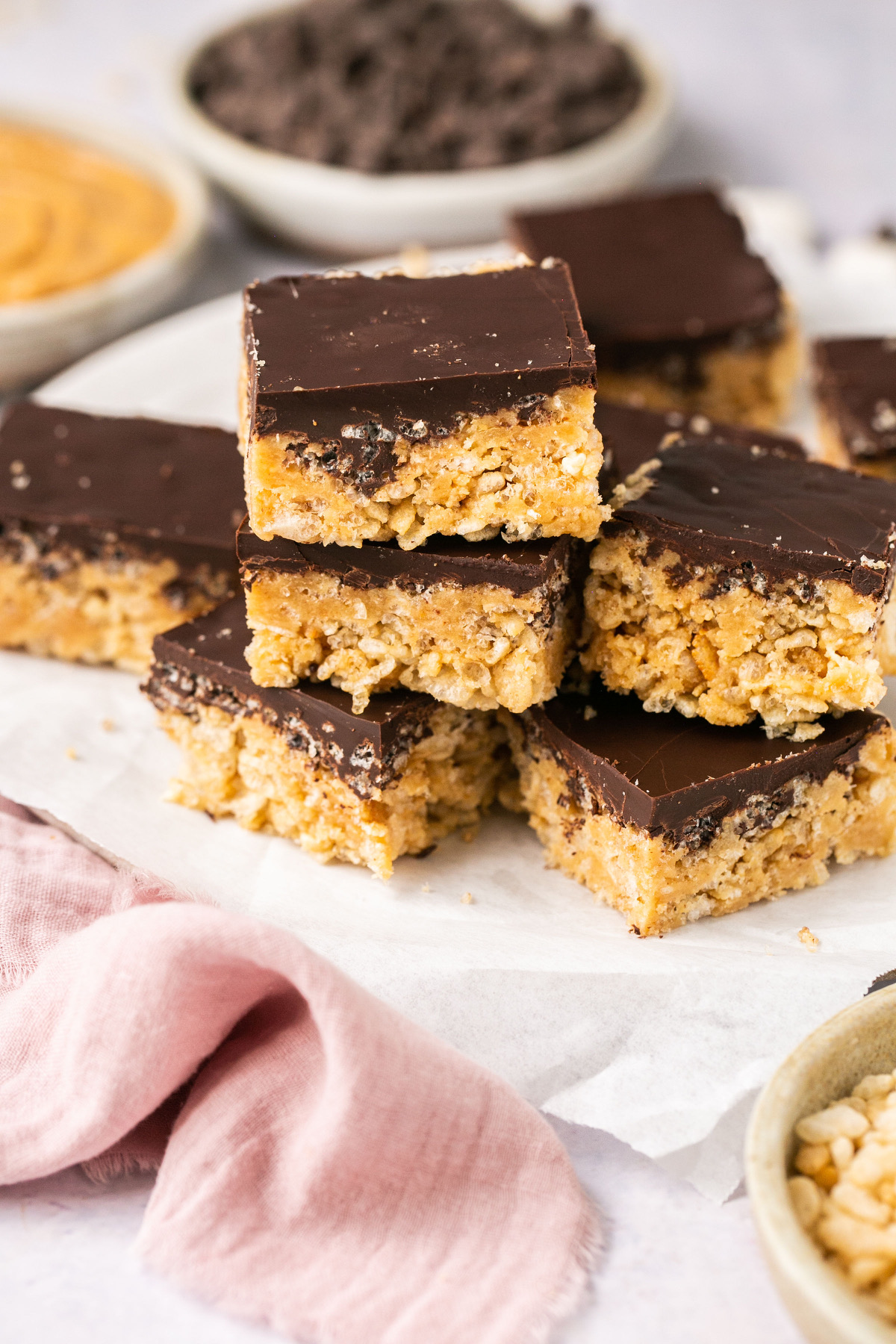 a stack of chocolate covered rice krispie treats on parchment paper