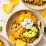 loaded taco skillet in a bowl with sour cream, avocado, and chips
