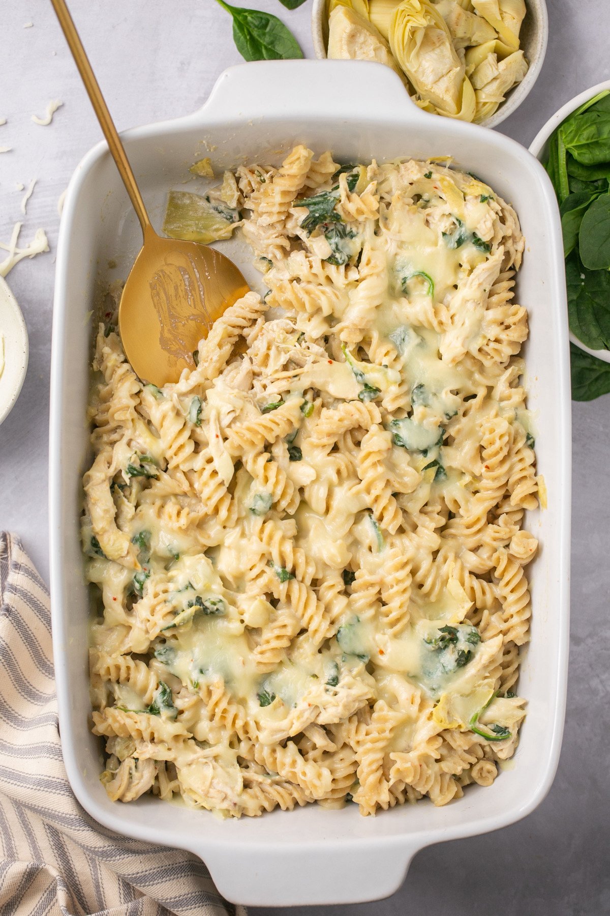 an overhead view of spinach artichoke chicken casserole in a white baking dish