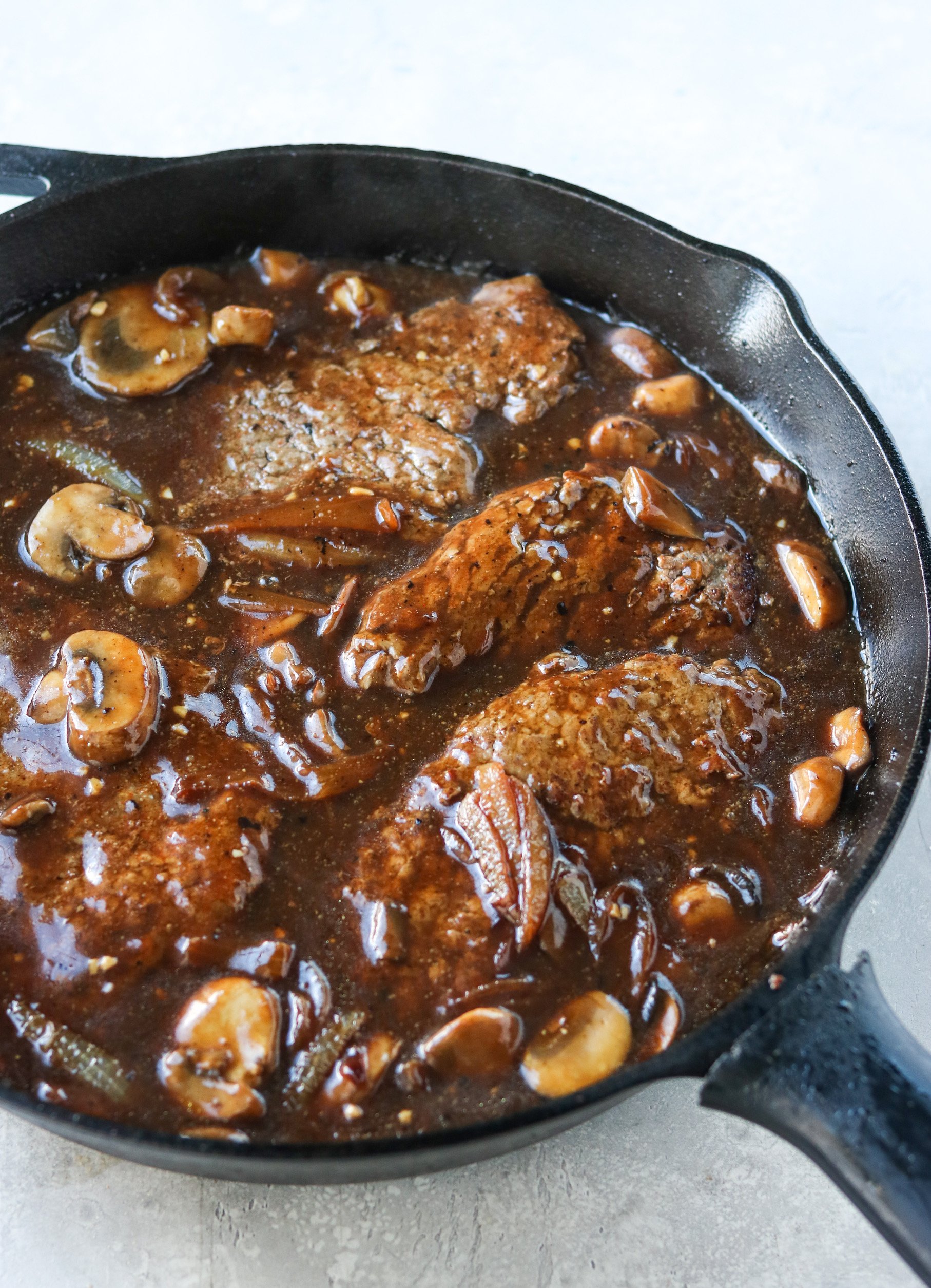 cubed steak with mushroom and onion gravy in a 12-inch cast iron skillet